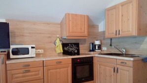 Een keuken met houten kastjes, een magnetron, een koffiezetapparaat en een vaatwasser.