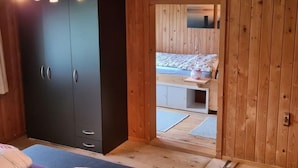 Ein Zimmer mit Holzboden, einem Bett, einem Kleiderschrank und einem kleinen Tisch.