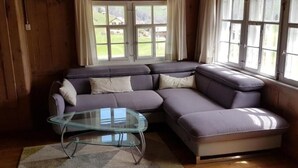 Ein Eckwohnzimmer mit einem modularen Sofa, einem Glastisch und einem gemusterten Teppich.