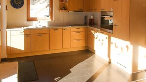 Cocina con armarios de madera, horno empotrado y ventana.