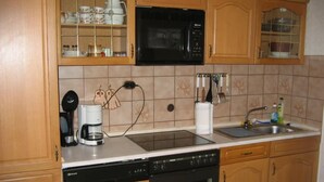 Una cocina con armarios de madera, microondas, cafetera y lavavajillas.