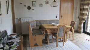 Un comedor con una mesa, sillas, un radiador y adornos en la pared.
