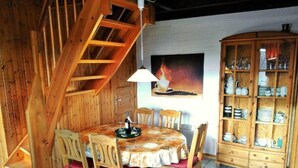 A wooden dining room with a table and chairs, a cabinet with dishes, and a staircase. - Vacation home Alissa by Interhome (Extertal)