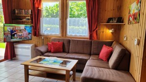 A cozy living room with a brown sofa, red cushions, a wooden coffee table, and a TV on a stand. - Vacation home Alissa by Interhome (Extertal)