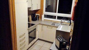 A compact kitchen with white cabinets, a built-in oven, a coffee maker, and a toaster. - Vacation home Alissa by Interhome (Extertal)