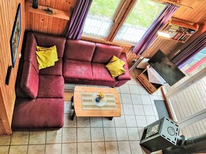 A cozy living room with a red sofa, a wooden coffee table, and a television. - Vacation home Merle by Interhome (Extertal)
