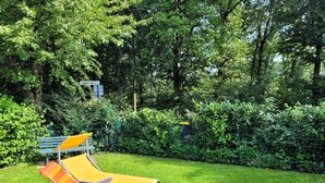 A grassy area with two orange and yellow striped lounge chairs and a green metal fence. - Vacation home Merle by Interhome (Extertal)