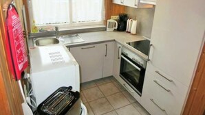 Eine kleine Küche mit einem Toaster, einem Backofen und einem Fenster mit Blick auf ein gelbes Gebäude.