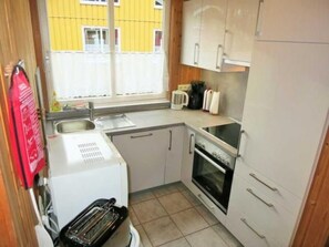 A compact kitchen with a toaster, oven, and a window with a yellow building view. - Vacation home Mia by Interhome (Extertal)
