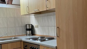 A kitchen with wooden cabinets, a gas stove, an oven, and a coffee maker. - Lisa am Silbersee  Silberseeblick by Interhome (Frielendorf)