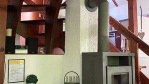 A cozy room with a wooden ceiling, a built-in wood stove, a small wooden table, and a metal chair. - Idyllisches Ferienhaus mit Balkon und Garten by Interhome (Frielendorf)