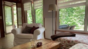 A cozy room with a white sofa, a wooden coffee table, and a bed with floral bedding. - Idyllisches Ferienhaus mit Balkon und Garten by Interhome (Frielendorf)