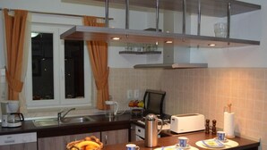 Een moderne keuken met een inbouwvaatwasser, een koffiezetapparaat, een broodrooster en een ontbijtgedeelte met borden, bekers en een mand met fruit.