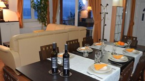 Een eethoek met een tafel voor vier personen, twee flessen wijn en een plant op de achtergrond.