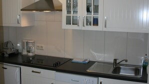 Eine moderne Küche mit weißen Schränken, einer Edelstahlspüle und einer Kaffeemaschine.