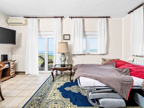 A bedroom with a bed, a desk, a television, and a view of the outdoors. - Vacation home Sara by Interhome (Plomin)
