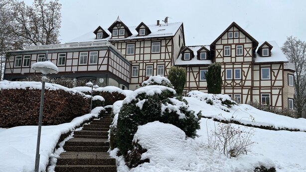 Un edificio tradicional con entramado de madera y una escalera cubierta de nieve que conduce a la entrada.