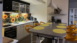 Una cocina moderna con una isla central, sillas amarillas y un salpicadero con motivos de girasol.