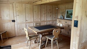 Ein Zimmer aus Holz mit einem großen Tisch, vier Stühlen, einem Schrank mit Spiegel und einem Bild an der Wand.