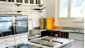 A modern kitchen with stainless steel appliances, white cabinetry, and a large island with a built-in stove.