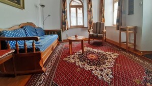 Ein gemütliches Zimmer mit einem hölzernen Bett, einem gemusterten Teppich, einem Sessel und einem kleinen Tisch.