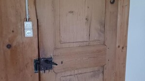 Une porte en bois avec un loquet métallique et une petite plaque rectangulaire au-dessus.