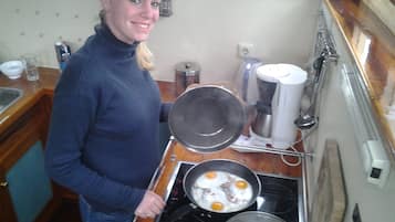 Een koelkast, een magnetron, een oven, kookgerei, borden en bestek