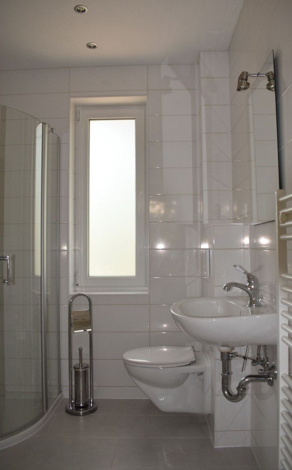 A modern bathroom with a glass shower enclosure, a toilet, and a sink.