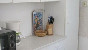 A kitchen with white cabinets, a coffee maker, a microwave, a basket, and a knife block. - mit Garten, Terrasse und Grill by Interhome (Plau am See)