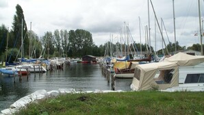 A marina with multiple boats docked, a tent, and a grassy area in the foreground. - mit Garten, Terrasse und Grill by Interhome (Plau am See)