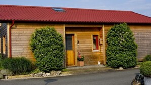 A wooden cabin with a red roof, a wooden door, and two large potted plants in front. - Relax Chalet by Interhome (Sint-Annaland)