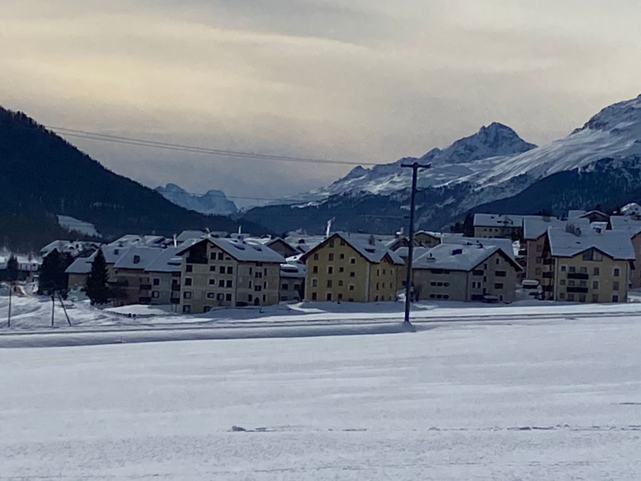 En snötäckt bergsby med flera våningar i byggnaderna, troligen en skidort.