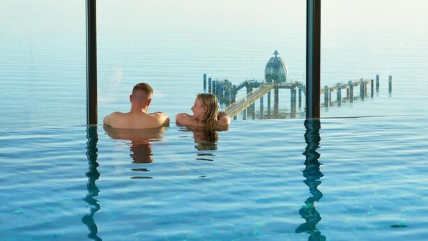 A couple in a large indoor pool with a view of a bridge and a dome structure in the background. - Meerblick&SPA by Interhome (Ostseebad Sellin)