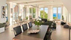 A spacious living area with a dining table, sofas, and a view of the sea. - Meerblick&SPA by Interhome (Ostseebad Sellin)