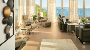 A modern living room with a view of the sea, featuring a sofa, armchairs, a coffee table, and a dining area. - Meerblick&SPA by Interhome (Ostseebad Sellin)
