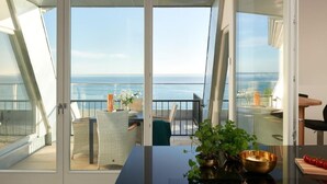 A modern balcony with a glass door, a dining table, chairs, and a view of the sea. - Meerblick&SPA by Interhome (Ostseebad Sellin)
