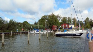 Uma marina com vários barcos atracados, um edifício vermelho e uma superfície de água calma.