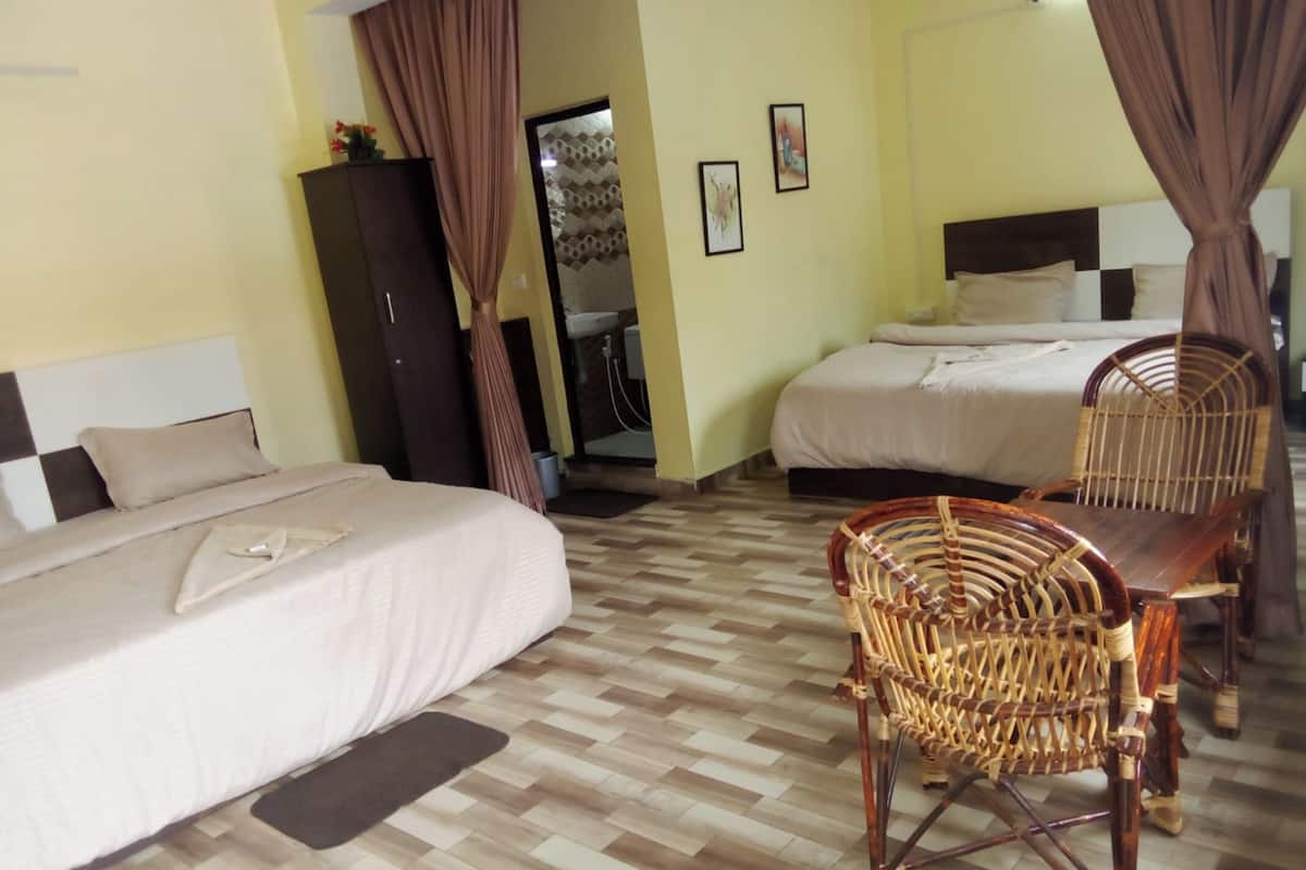 Een hotelkamer met twee bedden, een houten vloer, een rieten stoel en een kledingkast.