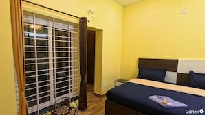 A bedroom with a bed, curtains, a window with blinds, and a nightstand. - Jeru Homes Ooty (Ooty)