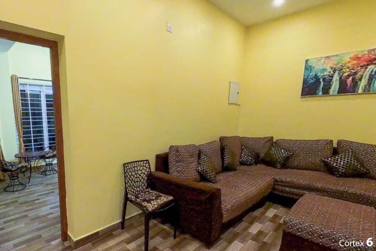 Een woonkamer met een bruine bank, decoratieve kussens, een gestreept fauteuil en een bijzettafeltje.