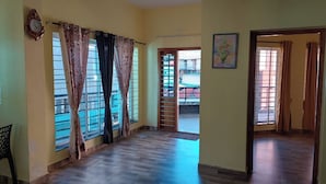 A spacious room with large windows, a wooden floor, and a door leading to an outdoor area. - Jeru Homes Ooty (Ooty)