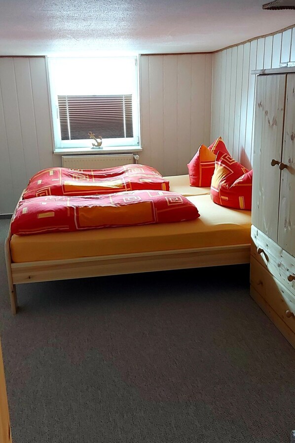 A small, single-bed room with a wooden floor, a window with blinds, and a wardrobe with a metal handle. - Apartment Fewo1 by Interhome (Born)