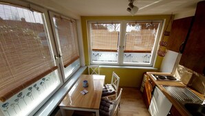 Une cuisine de taille réduite avec une table en bois, des chaises et une fenêtre équipée de stores.