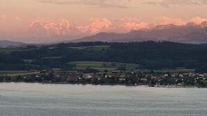 Et panoramaudsigt over en by ved søen med bjerge i baggrunden.