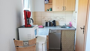Un angolo cottura compatto con microonde, macchina del caffè e lavastoviglie.