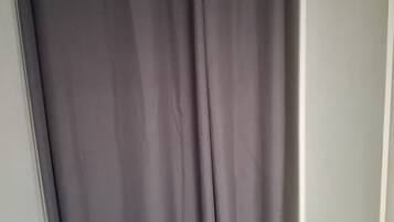 A room with a grey curtain, a white wardrobe, and a wooden floor.