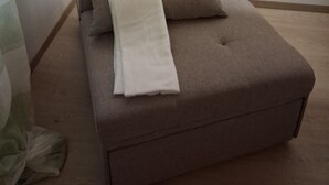 Ett modernt, minimalistiskt vardagsrum med en soffa och en vit pläd.