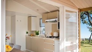 A compact kitchen with wooden cabinets, a gas stove, and a small refrigerator. - in Hohenlychen mit Grill, Loggia 3 by Interhome (Lychen)