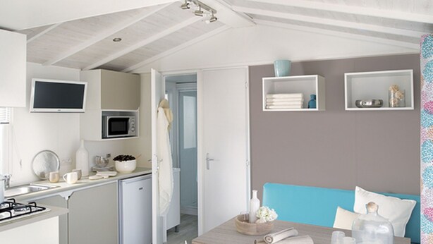 Une cuisine moderne équipée d’un four à micro-ondes, d’une cuisinière et d’un évier. Un coin repas avec une table et des chaises est également disponible.