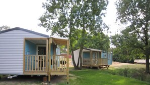 A mobile home with a porch and a small deck, surrounded by trees and grass. - Mobilheim Lagune I in Lychen by Interhome (Lychen)